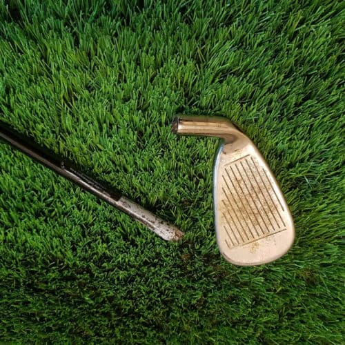 A broken golf club on top of grass