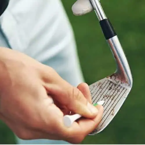 golfer cleaning golf club iron