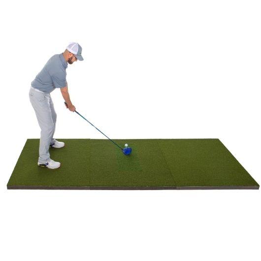 A golfer on a DIY golf simulator golf practice mat with a golf club, ball, and tee on white background