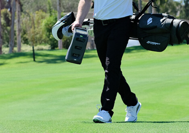 Golfer carrying a Foresight Sports GC3 Launch Monitor and a golf bag on the golf course
