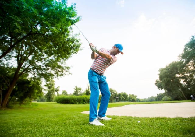Golfer about to swing his golf club to hit the golf ball on the golf coure