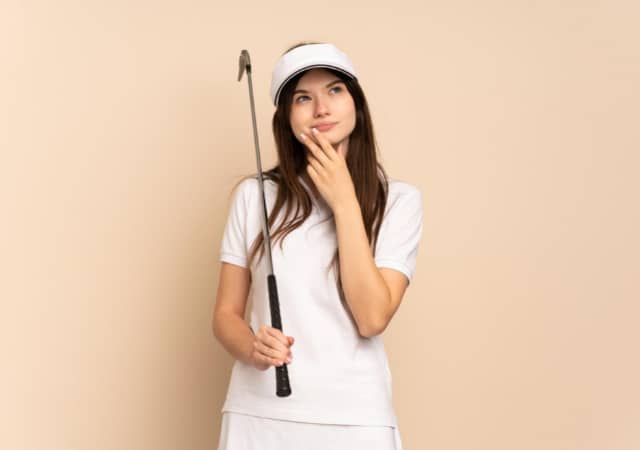 A golfer thinking while holding a golf club